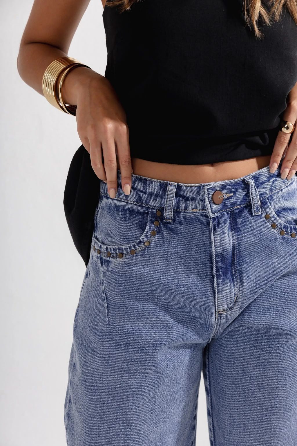 Detalhe dos bolsos da calça jeans com tachas douradas