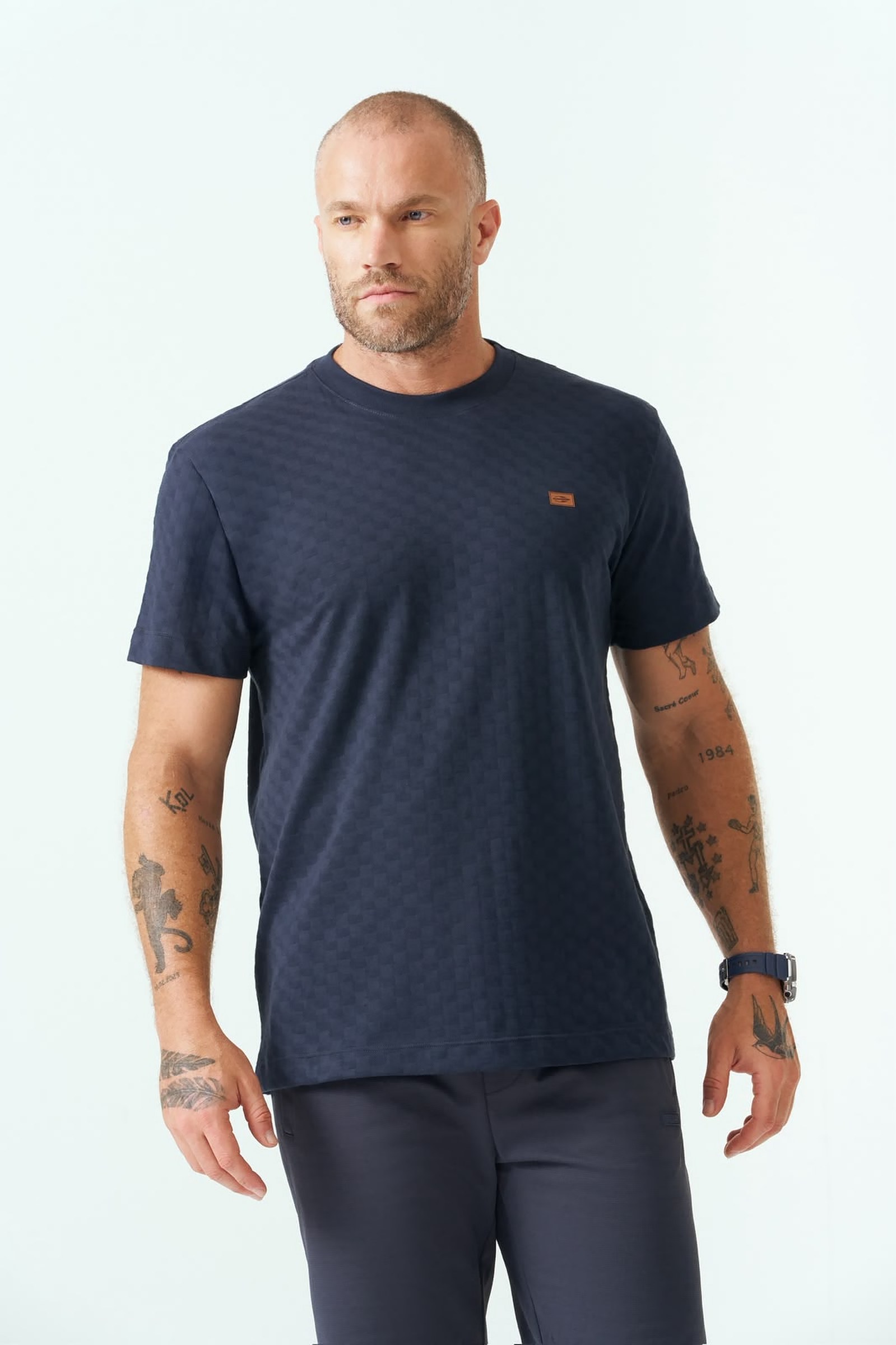 Homem usando camiseta azul marinho com textura quadriculada