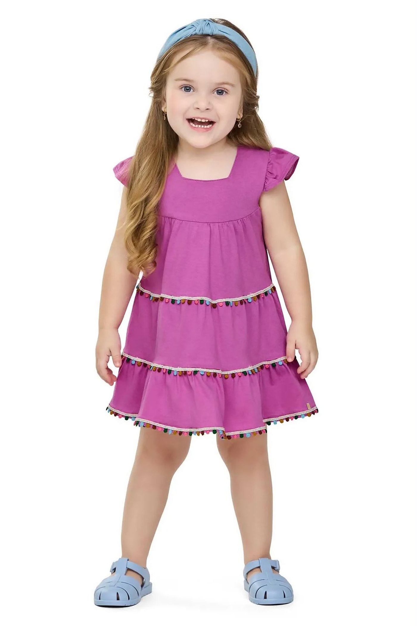 Menina usando vestido lilás em camadas com pompons coloridos