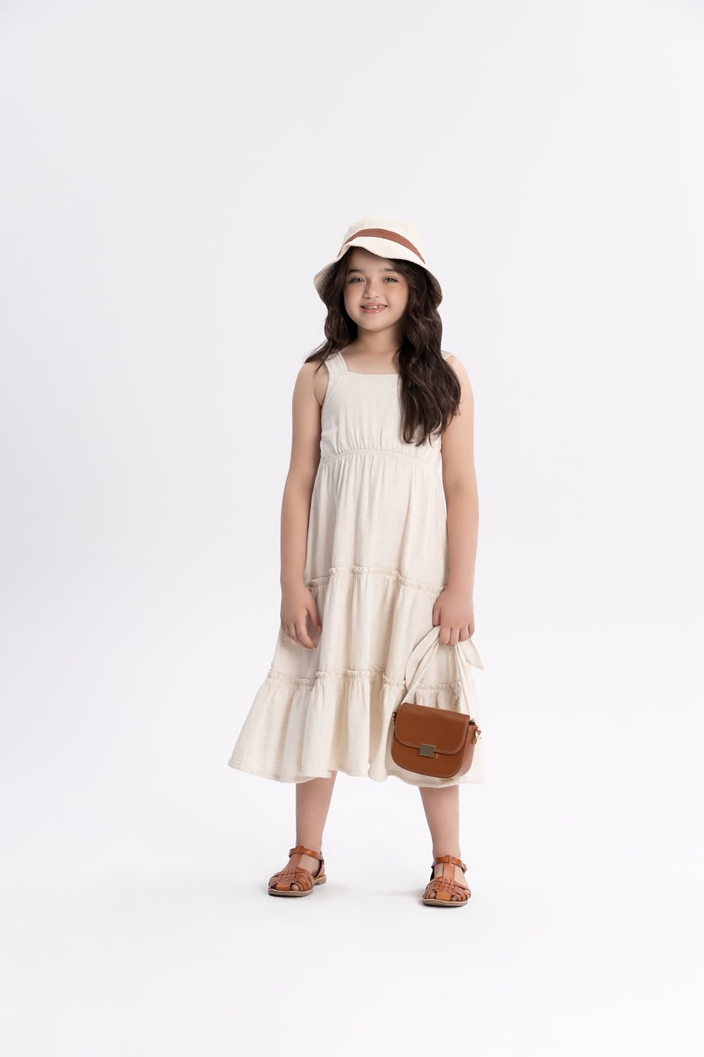 Menina usando vestido off white em camadas, chapéu e bolsa caramelo