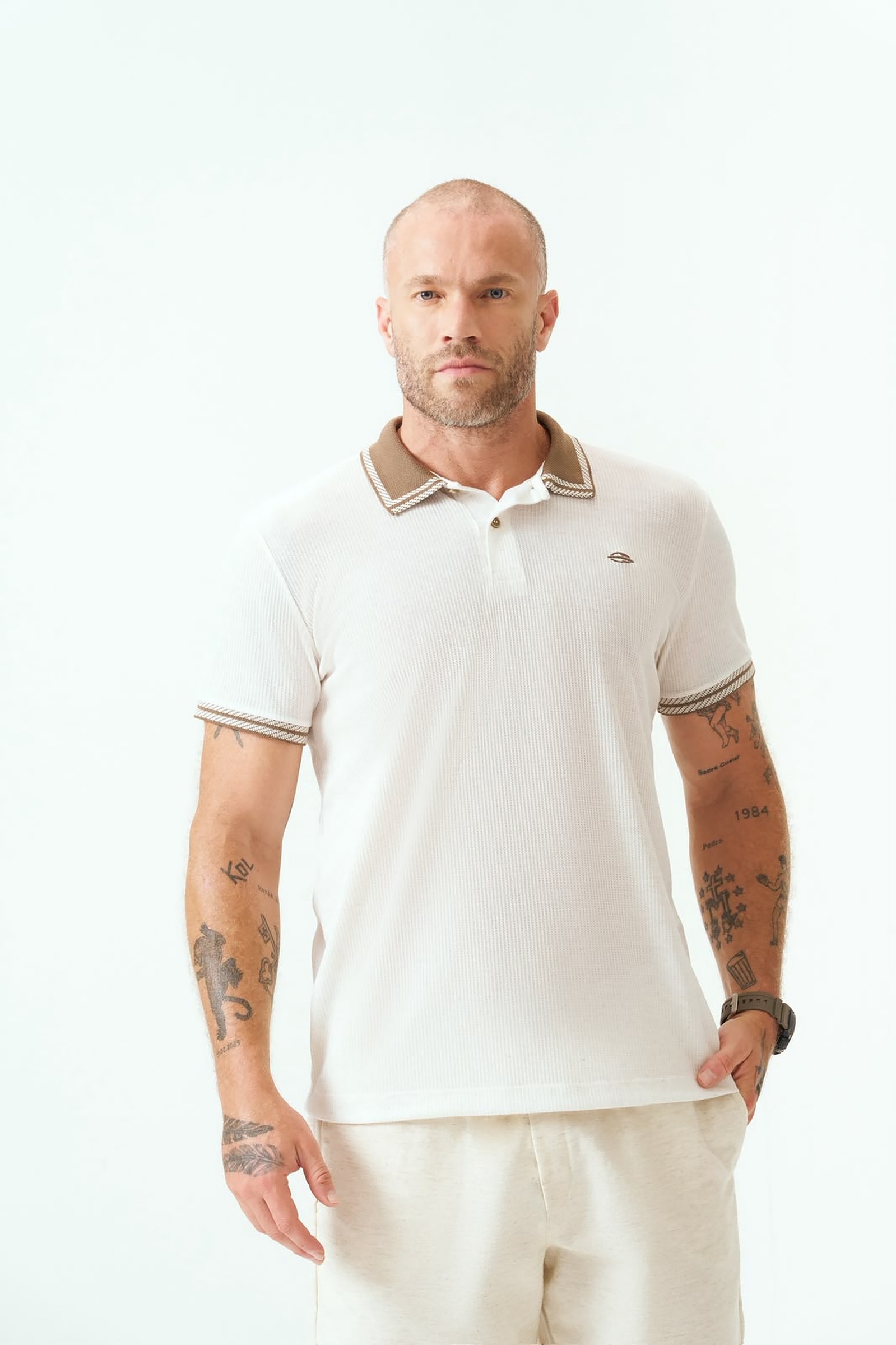Homem usando camisa polo off white texturizada com gola marrom listrada